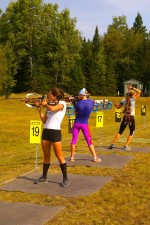 USBA skiers Corrine Malcolm (l), Annelies Cook (c) and Hannah Dreissigacker practice shooting during running intervals on Friday at Mt. Van Hoevenberg in Lake Placid, N.Y.