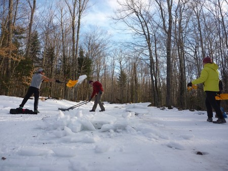 Members of the St. Lawrence University Ski Team shovel snow  onto the East Hill trail on Tuesday afternoon