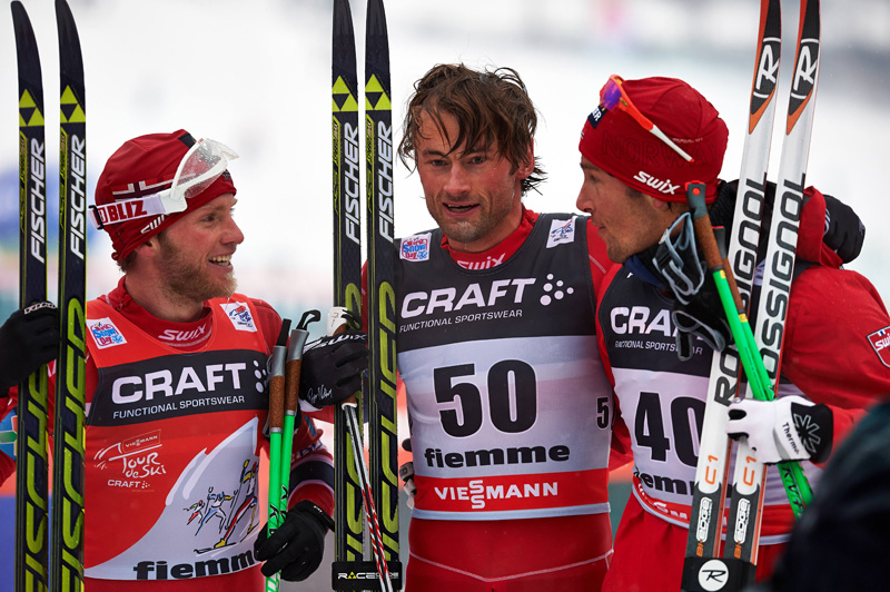 Northug (bib 50) is congratulated by teammates Martin Johnsrud Sundby (left) and Chris Jespersen (right) after the trio swept the podium in the 10 k classic race at the 2014 Tour de Ski. Photo: Fischer / Nordic Focus.