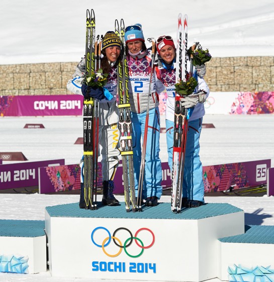 Heidi Weng on the podium in the skiathlon at the 2014 Olympic Games, along with Norwegian teammate Marit Bjørgen and Sweden's Charlotte Kalla. (Photo: Fischer/NordicFocus)