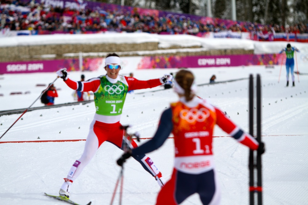 Marit Bjørgen (l) skis toward her Norwegian teammate in Wednesday's Olympic 6 x 1.3 k classic team sprint, Ingvild Flugstad Østberg after anchoring the team to its first-ever team sprint victory at the Olympics.  