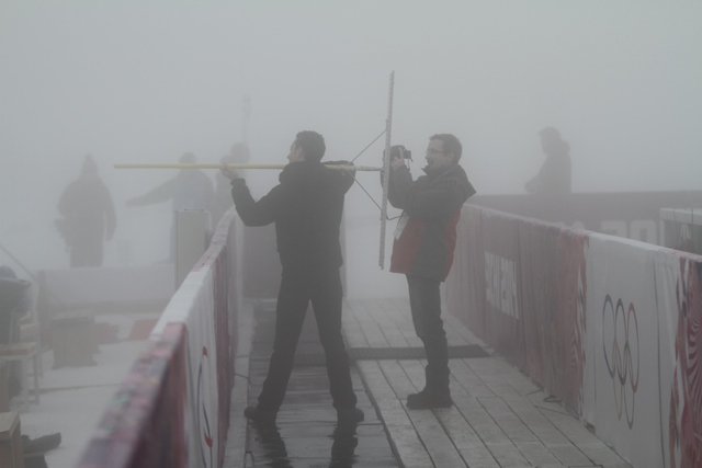 Journalists pose for pictures of what it might be like to try to shoot on the range, grabbing a snow rake - heavily used to smooth out the slushy snow so far this week - as a prop.