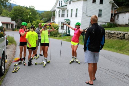 Canadian World Cup Team coach Tor-Arne Hetland (r) talks with the SMST2 Team during a water stop on its over-distance rollerski session on Aug. 15 near Stratton, Vt.
