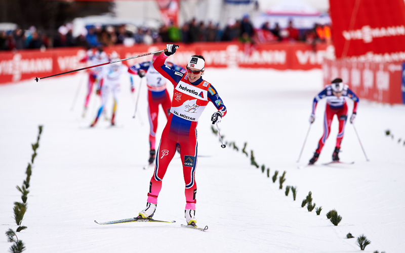 Marit Bjoergen (NOR) celebrates another victory in the 2015 Tour de Ski, crossing the finish line in Val Mustair, Switzerland.  (photo: Fischer/Nordic Focus)