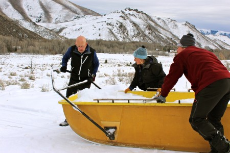 (Left to right): Mel Dyke (volunteer), Kate Barton (Burke Mountain Academy coach) and Colin Rogers (SVSEF Gold Team head coach) push a sled full of snow on Wednesday afternoon to dump onto the SuperTour 10/15 k  classic distance race course in Sun Valley, Idaho. 