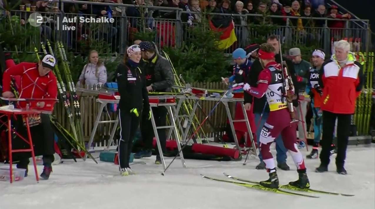 Canada Biathlon’s Megan Tandy (in black) greets her relay partner Macx Davies in the tech service area after the mass start race during the 2016 Biathlon auf Schalke invitational event. (Photo: ZDF broadcast)