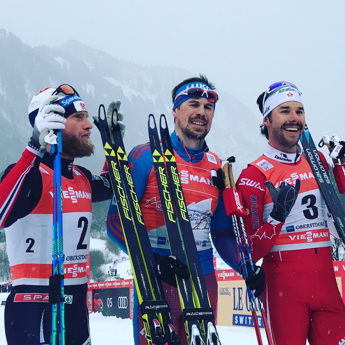 The men's 15 k freestyle pursuit podium at Stage 4 of the Tour de Ski in Oberstdorf, Germany, with Russian winner Sergey Ustiugov (c), Norway's Martin Johnsrud Sundby (l) in second, and Canada's Alex Harvey (r) in third. (Photo: FIS Cross Country/Twitter)
