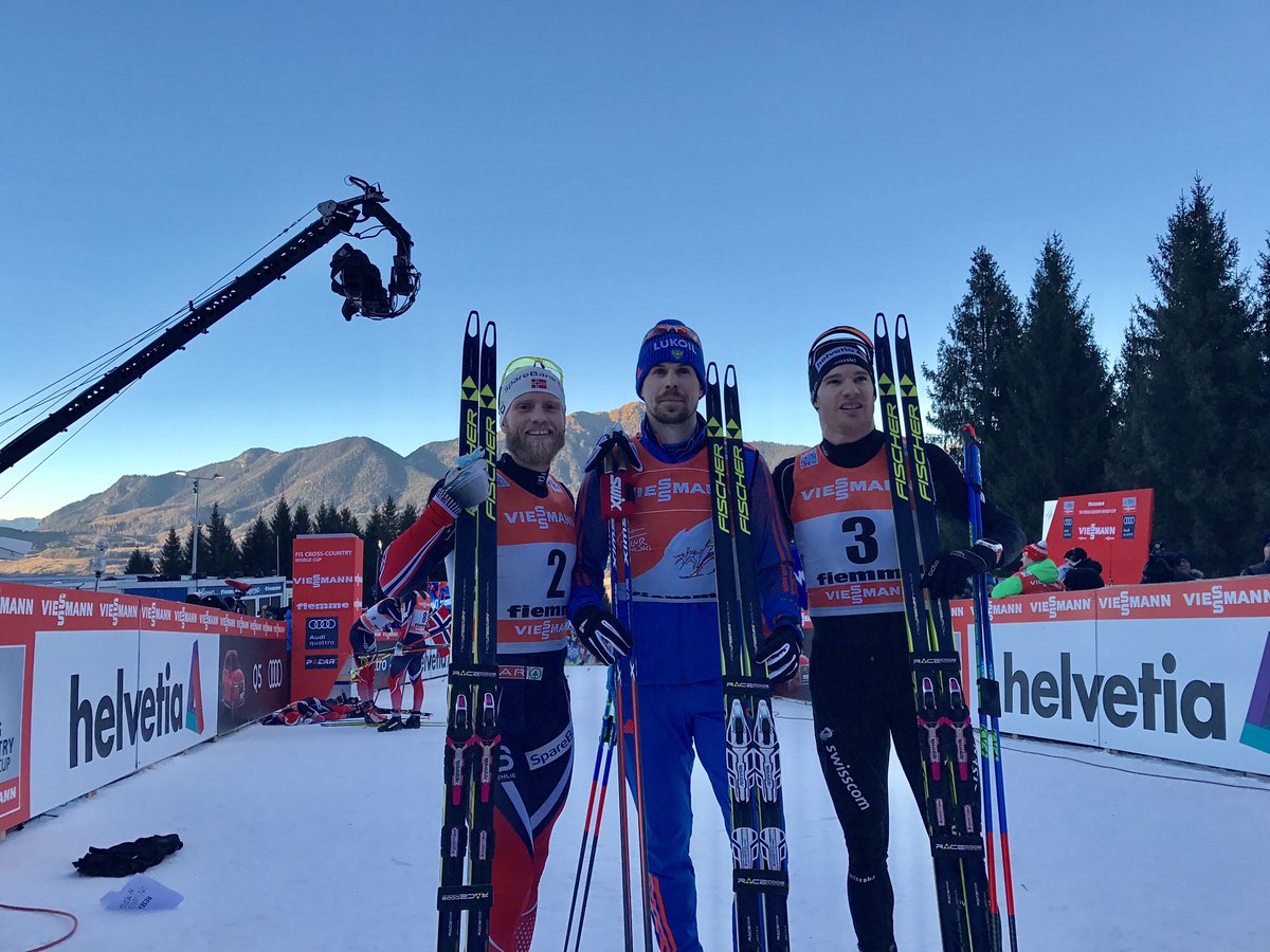 The overall podium at the end of the 2017 Tour de Ski, with winner Sergey Ustiugov (c) of Russia, Norway's Martin Johnsrud Sundby (l) in second, and Switzerland's Dario Cologna (r) in third after finishing in that order in the 9 k freestyle hill-climb pursuit, Stage 7 of the Tour de Ski in Val di Fiemme, Italy. (Photo: FIS Cross Country/Twitter)