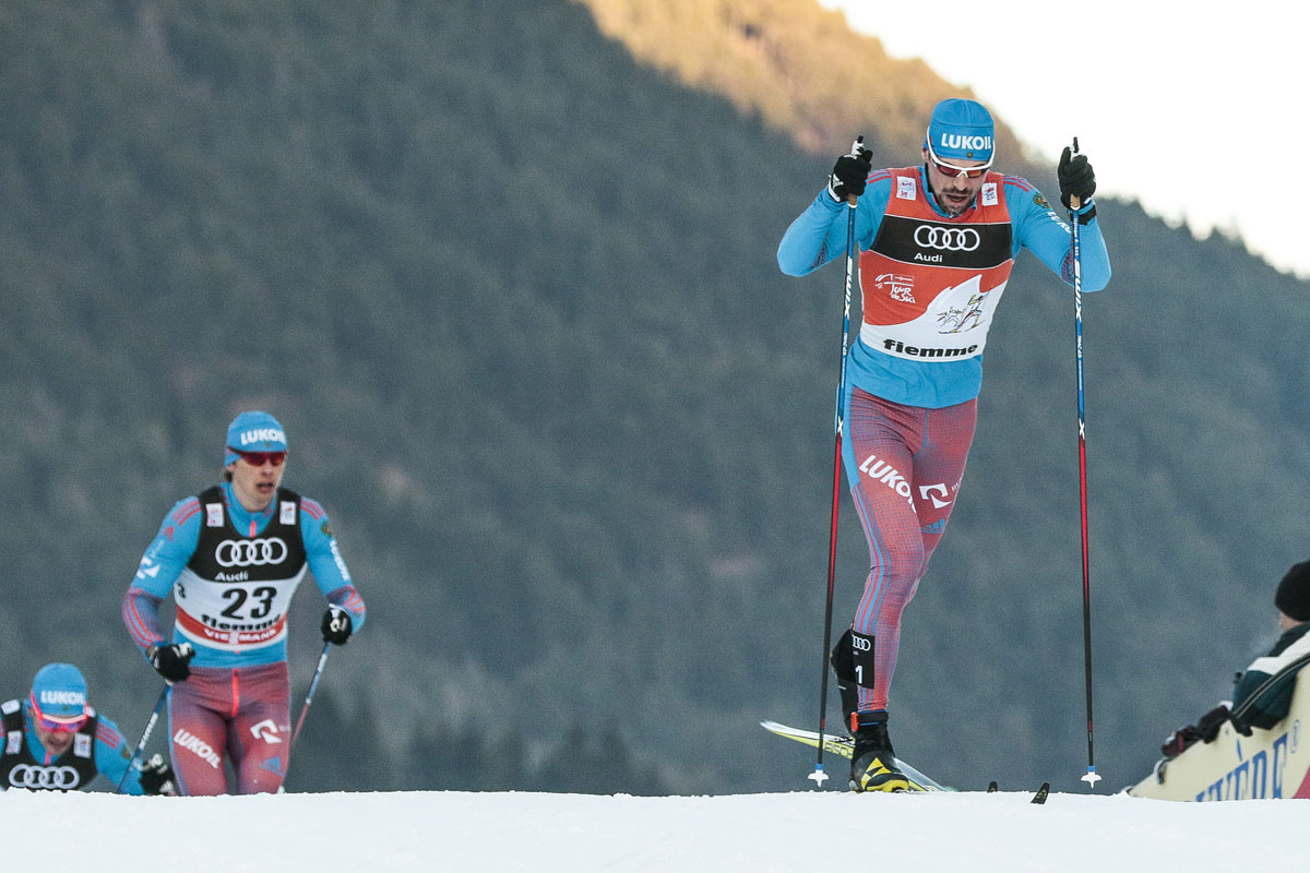 Russia's Sergey Ustiugov leads his Russian teammates Alexander Bessmertnykh (23) and Alexey Larkov at the front of the pack during the men's 15 k classic mass start at Stage 6 of the Tour de Ski in Val di Fiemme, Italy. (Photo: Fischer/Nordic Focus)
