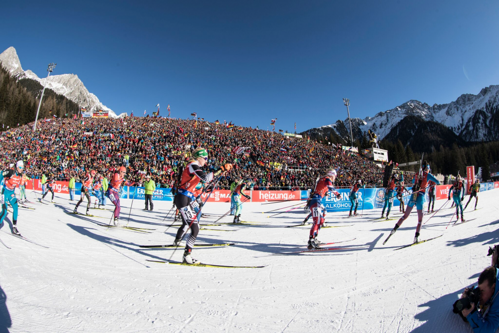 US Biathlon’s Susan Dunklee (bib 17, orange & purple suit) skiing past the crowded stands at the start of the women’s 12.5 k mass start at the 2017 IBU World Cup in Antholz, Italy. (Photo: IBU/Christian Manzoni)