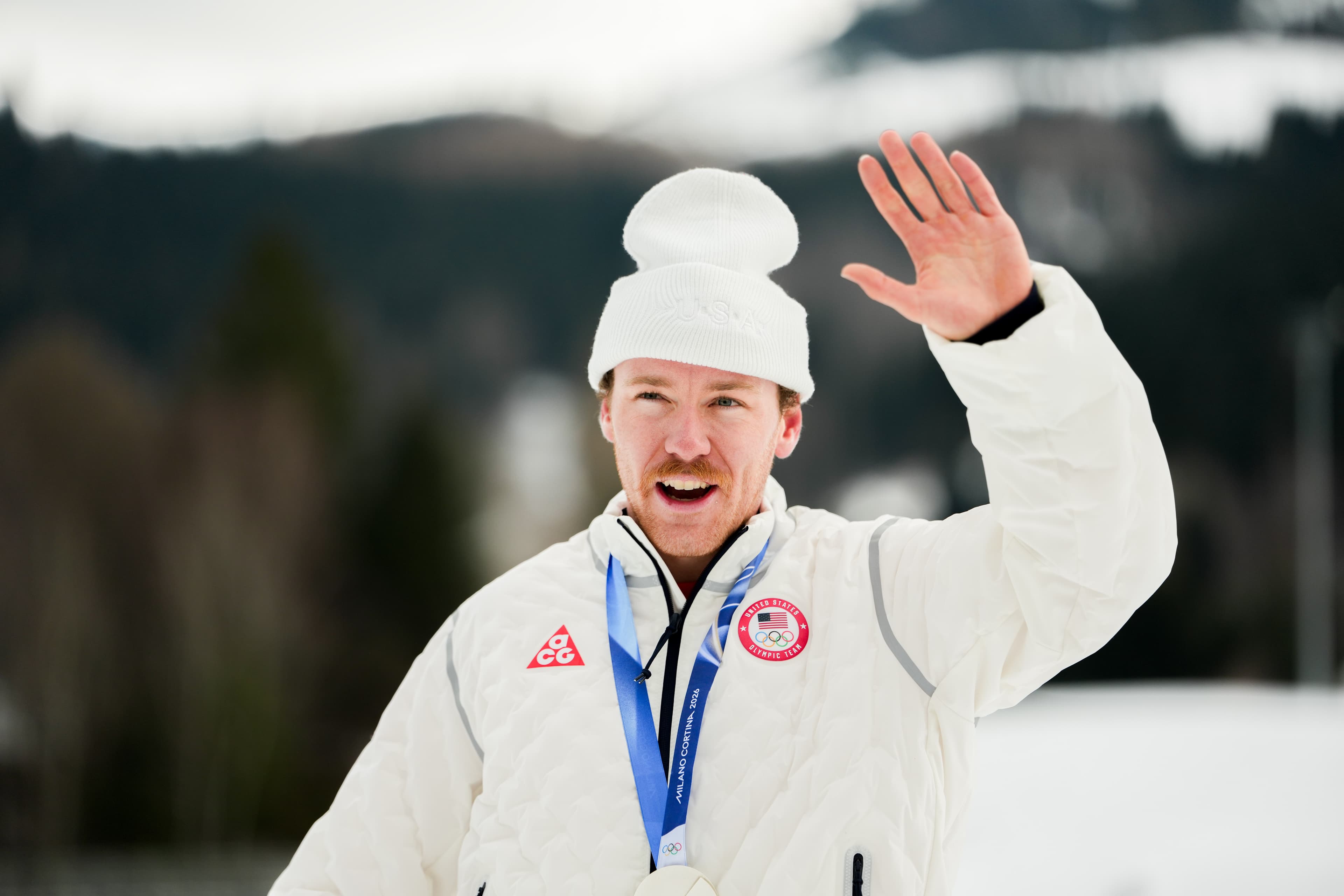 Ben Ogden waving from the Olympic medal ceremony with his silver medal