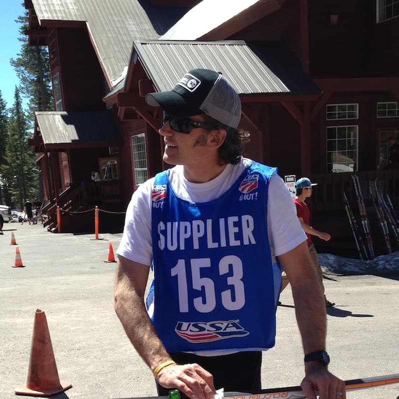 Randy Gibbs in sunglasses, a cap and a blue USSA supplier bib at a spring ski race