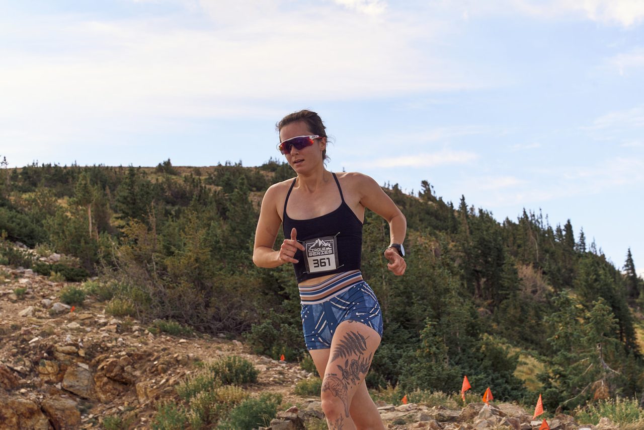 Kendall Kramer running uphill on a rocky mountain course wearing race bib 361.